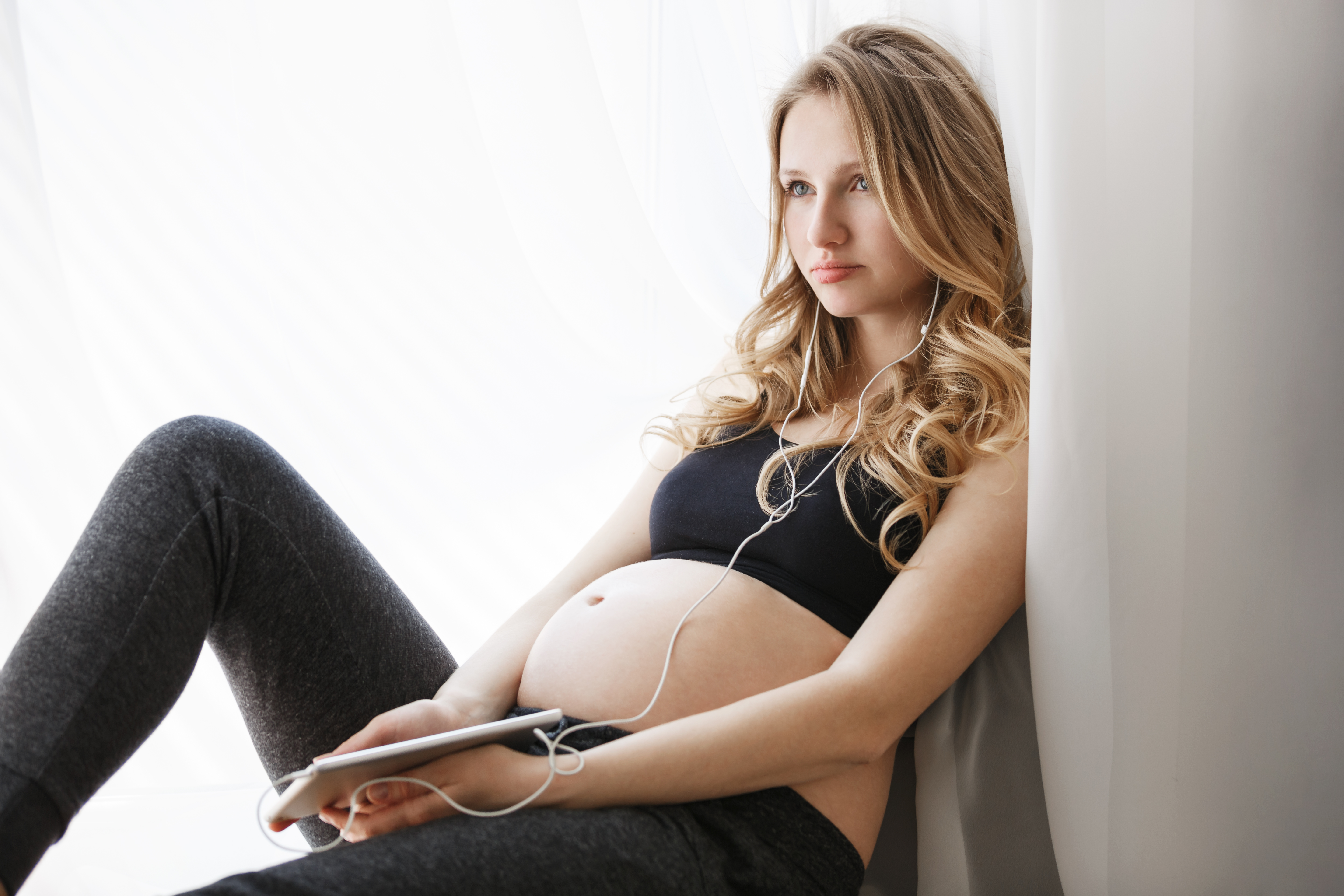 Pregnant young woman sitting by window, listening to music, reflecting on estranged dad and reconnecting with daughter story. Pregnant young woman sitting by window, listening to music, reflecting on estranged dad and reconnecting with daughter story.