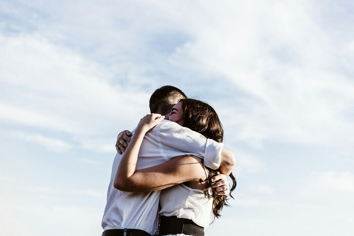 A man and woman hugging outdoors under a blue sky, illustrating common gender-based double standards in society.