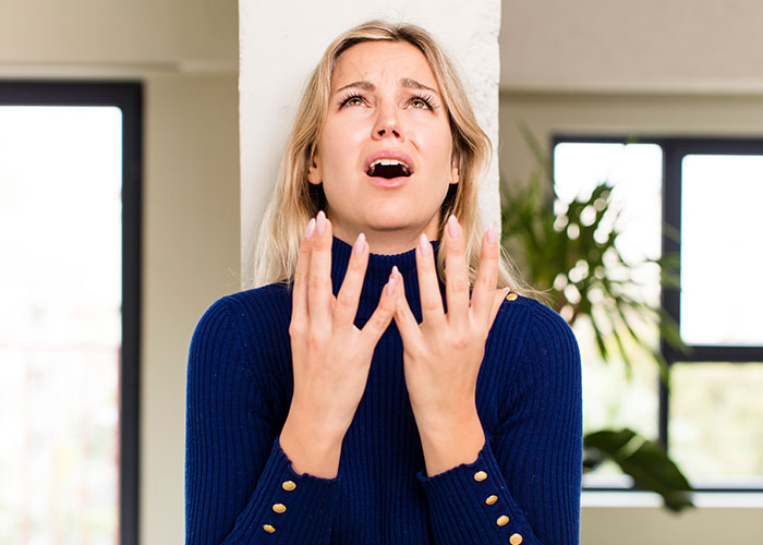 Young woman in a blue sweater looking fearful and anxious, representing real-life terror and paranoia.