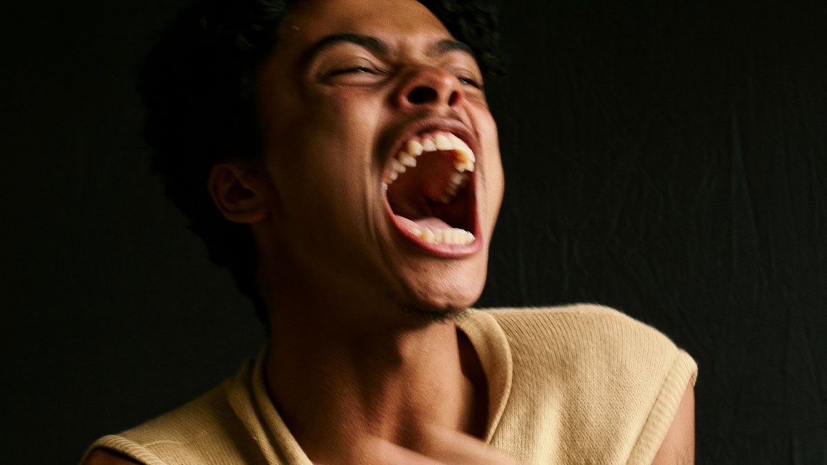 Man yelling intensely against a dark background, illustrating behaviors from men that might make women feel unsafe.