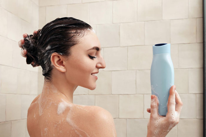Woman washing hair with shampoo in shower, showing how to refuse female friend using shampoo politely.