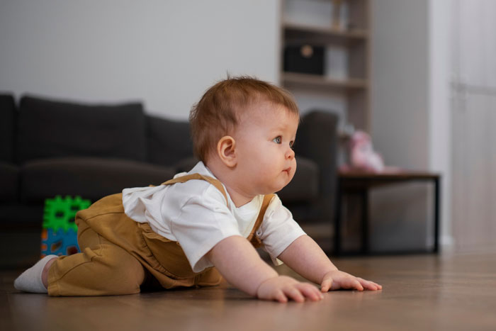 Baby crawling indoors on wooden floor, illustrating a medical condition related to shoes in a friend's house scenario. Baby crawling indoors on wooden floor, illustrating a medical condition related to shoes in a friend's house scenario.