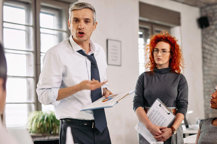 Man in office discussing career risks while colleague listens, highlighting Indian guy refusing to change name for US client.