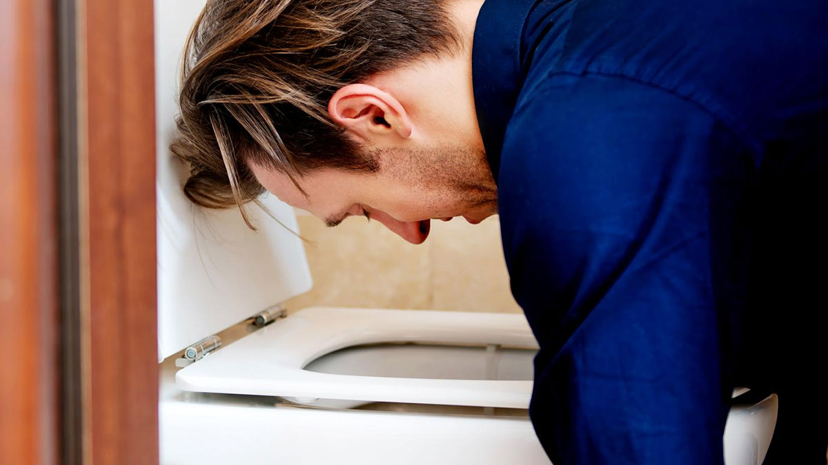 Man leaning over toilet bowl appearing sick, illustrating tension in a mother caring for 10-month-old scenario.