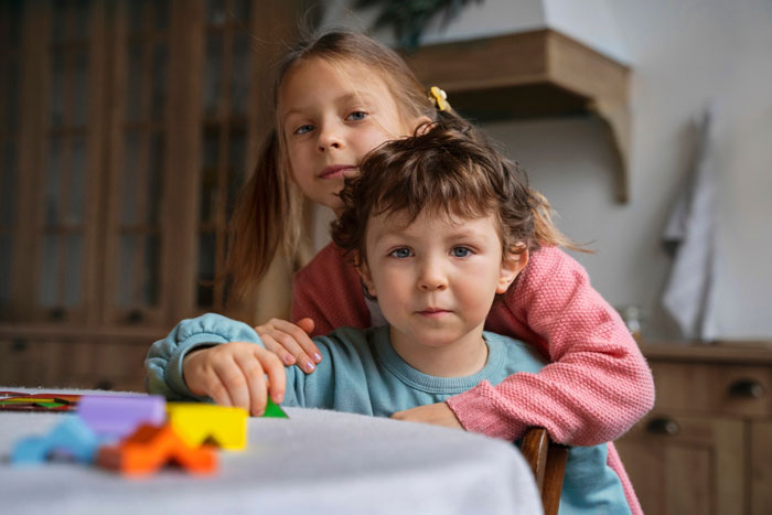 Two young children at a table, highlighting the story of 16YO twins missing out on teen life due to babysitting duties. Two young children at a table, highlighting the story of 16YO twins missing out on teen life due to babysitting duties.