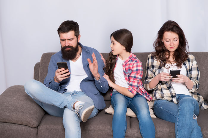 Father ignoring daughter while sister and mom use phones on couch showing relationship siblings sister mom dynamics. Father ignoring daughter while sister and mom use phones on couch showing relationship siblings sister mom dynamics.