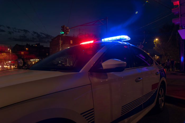 Police car with flashing lights at night, symbolizing response to domestic violence accusations and emotional distress. Police car with flashing lights at night, symbolizing response to domestic violence accusations and emotional distress.