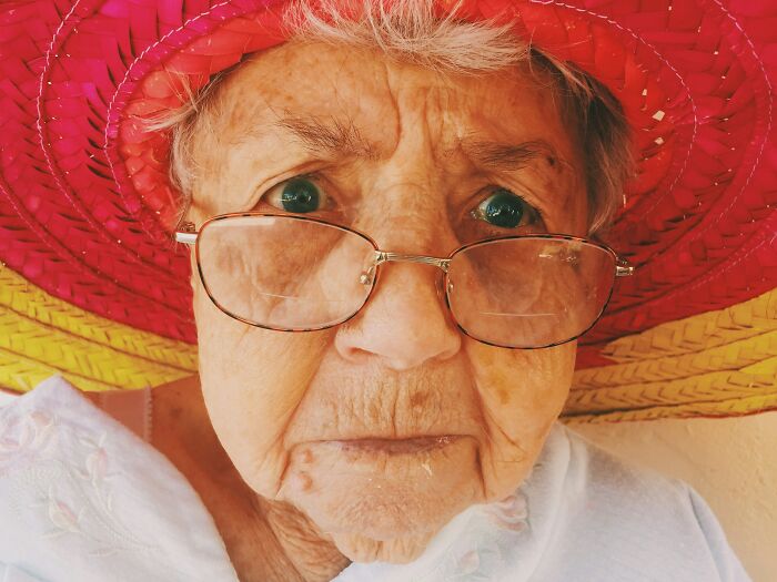 Close-up of an elderly person wearing glasses and a colorful hat, representing people recalling gross and unexpected things witnessed.