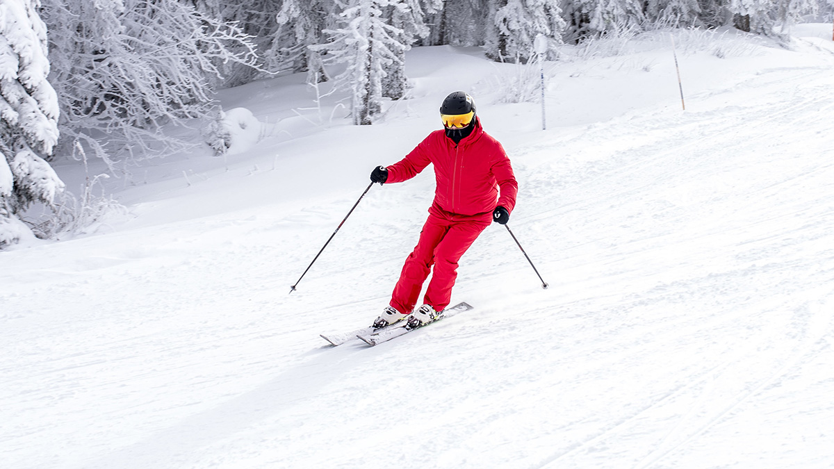 Skier in bright red outfit skiing on snowy slope surrounded by frosted trees, illustrating moments rich people realize differences.