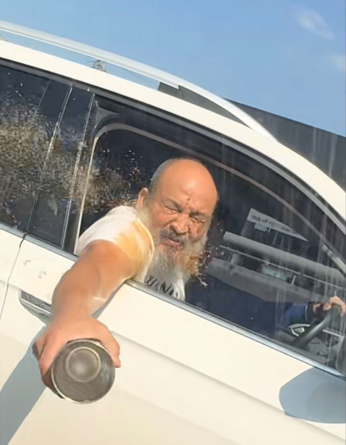 Man in a car aggressively tossing coffee out the window, capturing a moment of road rage instant karma in traffic. Man in a car aggressively tossing coffee out the window, capturing a moment of road rage instant karma in traffic.