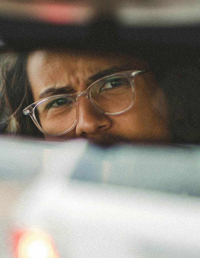 Man wearing glasses looking intensely through a car rearview mirror during a road rage moment and coffee toss incident. Man wearing glasses looking intensely through a car rearview mirror during a road rage moment and coffee toss incident.