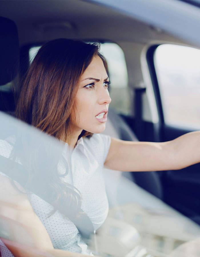Angry woman driving a car, showing road rage, frustrated and yelling while gripping the steering wheel intensely. Angry woman driving a car, showing road rage, frustrated and yelling while gripping the steering wheel intensely.