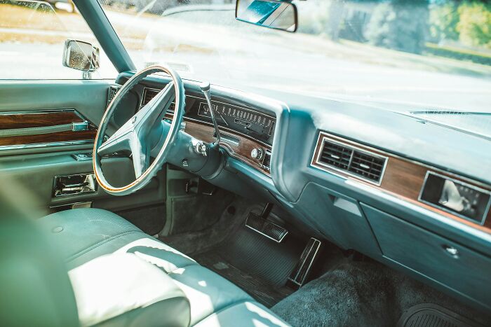 Vintage car interior featuring a wooden steering wheel and dashboard, showcasing ingenious inventions repurposed over time.