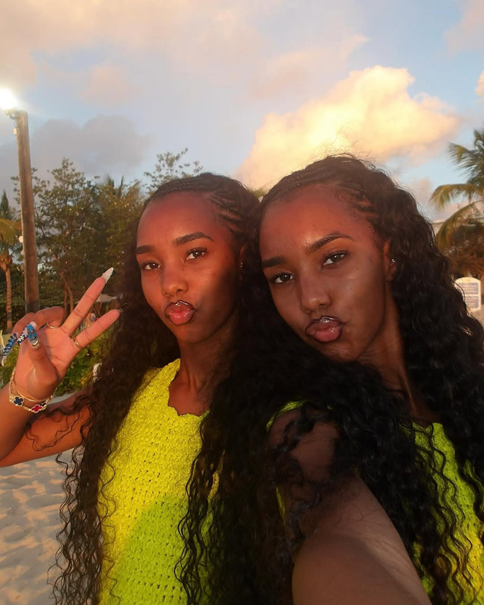 Twin daughters of Sean Diddy Combs posing together outdoors with long curly hair and bright yellow tops. Twin daughters of Sean Diddy Combs posing together outdoors with long curly hair and bright yellow tops.