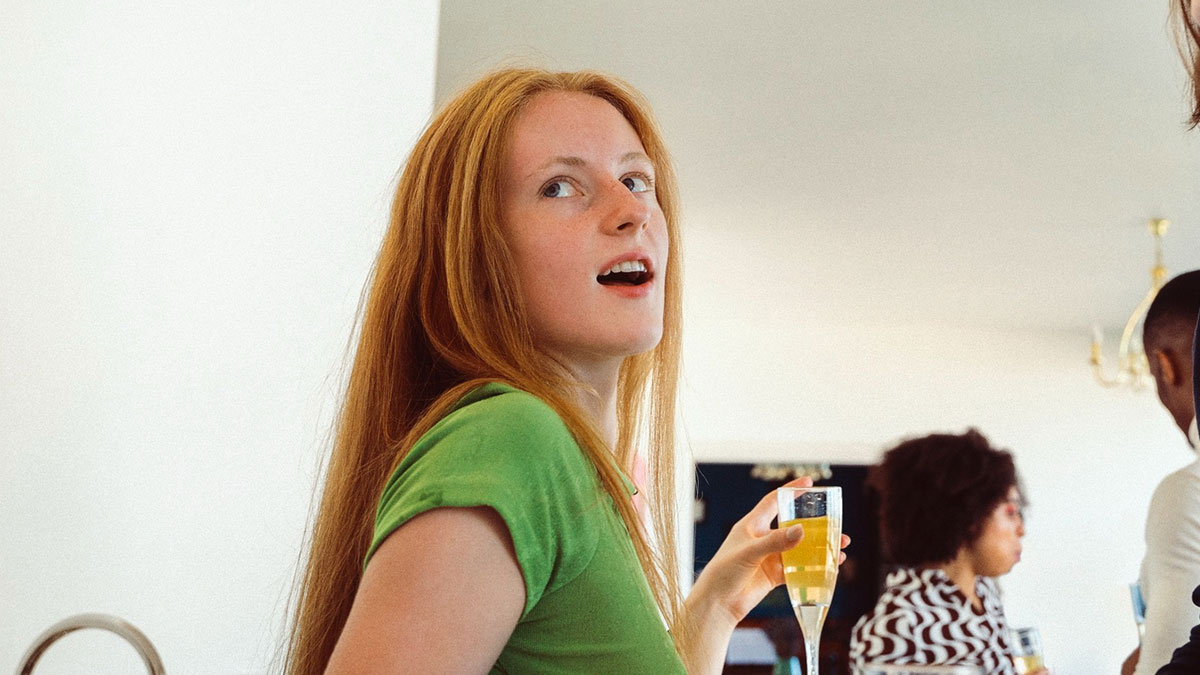 Young woman in a green shirt holding a glass, capturing a moment related to adopted sis chosen one joke backfiring.