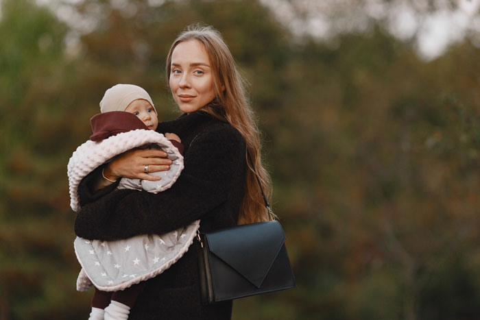 Young woman holding a baby outdoors, portraying a 19-year-old basically raising sister's kid and caring for her. Young woman holding a baby outdoors, portraying a 19-year-old basically raising sister's kid and caring for her.
