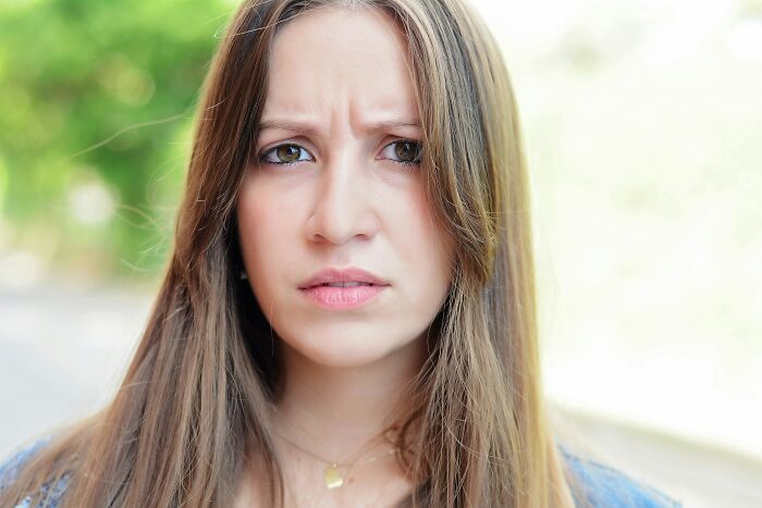 Young woman with long hair showing a concerned expression, reflecting feelings about brother swapping wife and kids for new flame. Young woman with long hair showing a concerned expression, reflecting feelings about brother swapping wife and kids for new flame.