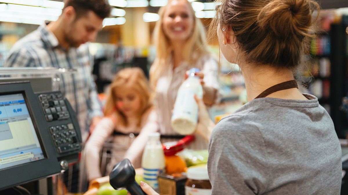 Woman holding a bottle at a grocery store checkout, illustrating picking the wrong line in the store experience.