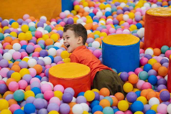 Young child playing in a colorful ball pit, representing woman on a 12-month hiatus from work and financial expectations. Young child playing in a colorful ball pit, representing woman on a 12-month hiatus from work and financial expectations.