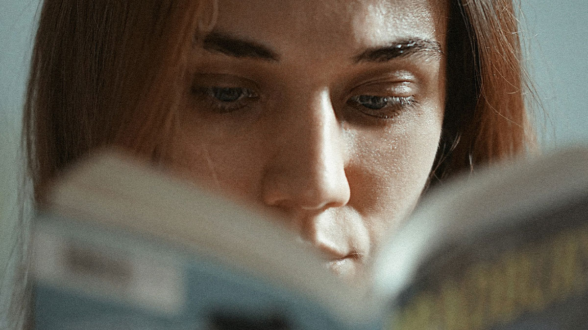 Young woman intensely reading a book about glitches in the matrix, focused on unusual and hard to believe experiences.