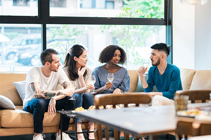 Group of friends sitting on a couch having a serious conversation about resentment and a trip one did not want to take. Group of friends sitting on a couch having a serious conversation about resentment and a trip one did not want to take.