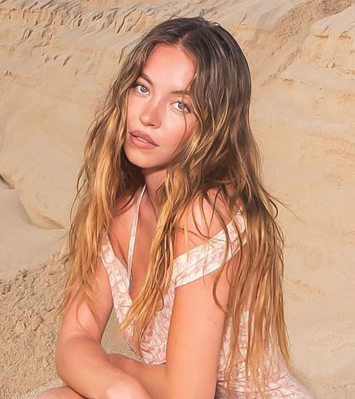 Young woman with long wavy hair in a pink dress posing against a sandy background, reflecting genes with bad taste theme. Young woman with long wavy hair in a pink dress posing against a sandy background, reflecting genes with bad taste theme.