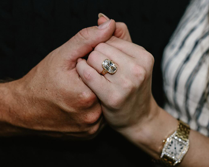 Close-up of hands holding each other, featuring a large engagement ring and wristwatch, highlighting body language expert insights. Close-up of hands holding each other, featuring a large engagement ring and wristwatch, highlighting body language expert insights.