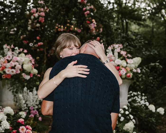 Taylor Swift and Travis Kelce hugging warmly in a floral garden, showing body language expert insights on their connection. Taylor Swift and Travis Kelce hugging warmly in a floral garden, showing body language expert insights on their connection.
