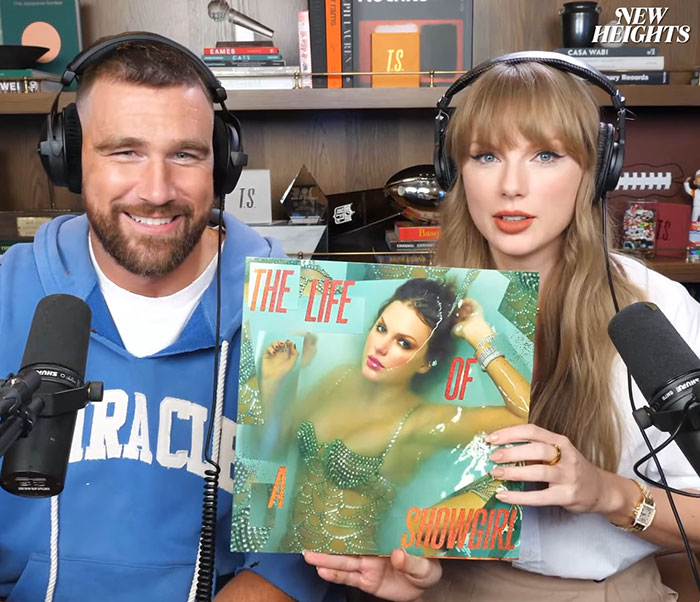Two podcasters wearing headphones hold Taylor Swift's new cover art amid discussion of controversy and young daughter idolization concerns. Two podcasters wearing headphones hold Taylor Swift's new cover art amid discussion of controversy and young daughter idolization concerns.