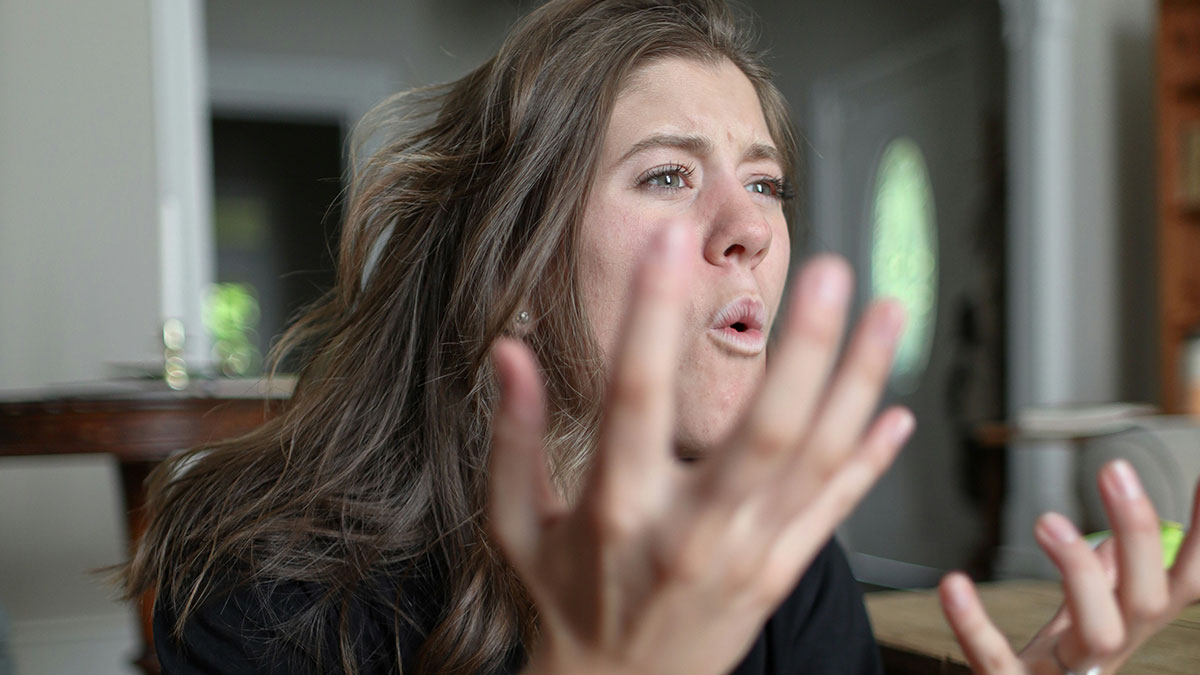 Young woman expressing frustration indoors, illustrating family fallout after person tells half-sister they ran away because of her.