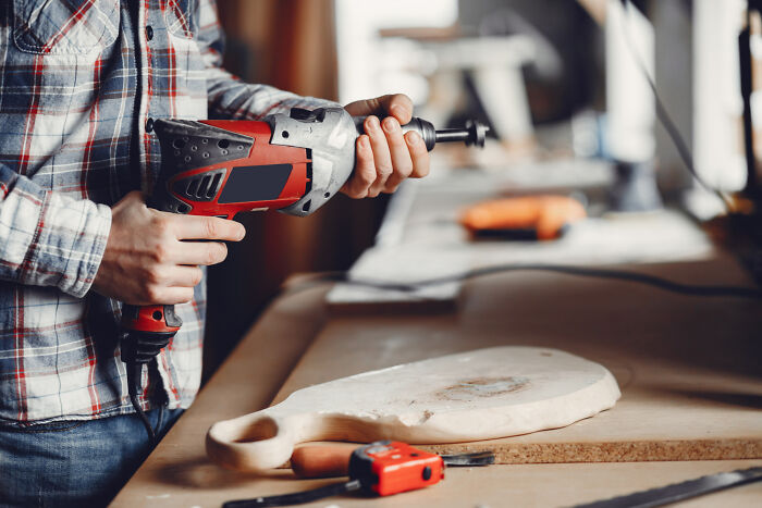 Person holding a power drill near a wooden board, evoking childhood memories that felt sweet but became unsettling in retrospect.