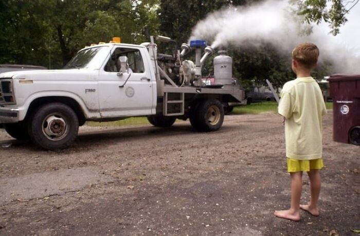 Young barefoot child watching a fogging truck spraying chemicals, evoking childhood memories that now feel unsettling in retrospect.