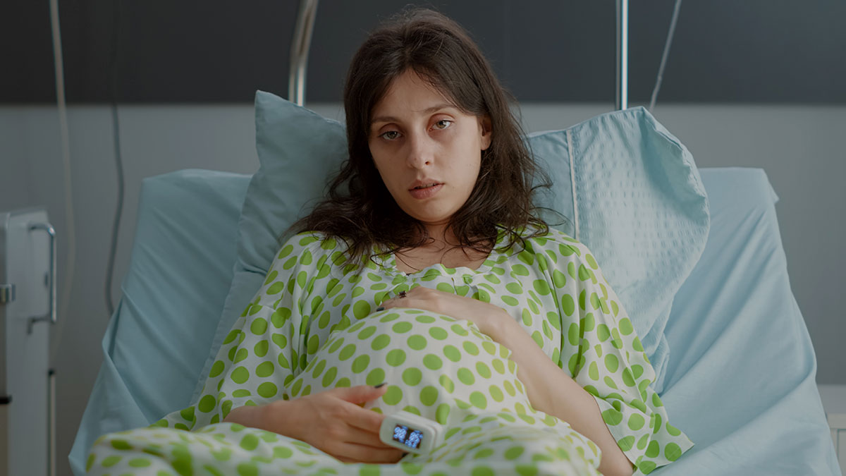 Woman in hospital bed looking distressed, representing a woman appalled by dadu2019s reaction to her dead grandchild