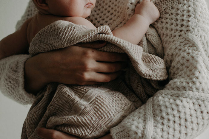 Close-up of a person holding a baby wrapped in a knitted blanket, illustrating common tourist traps themes. Close-up of a person holding a baby wrapped in a knitted blanket, illustrating common tourist traps themes.
