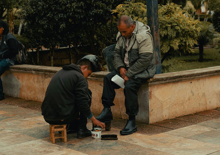 Man shining shoes outdoors in a public area, illustrating a common tourist trap scene with shoe cleaning services. Man shining shoes outdoors in a public area, illustrating a common tourist trap scene with shoe cleaning services.