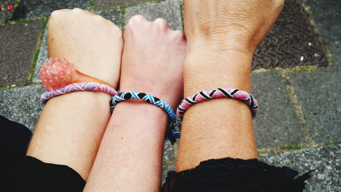 Three wrists wearing colorful handmade bracelets, illustrating common tourist traps and souvenir purchases outdoors. Three wrists wearing colorful handmade bracelets, illustrating common tourist traps and souvenir purchases outdoors.