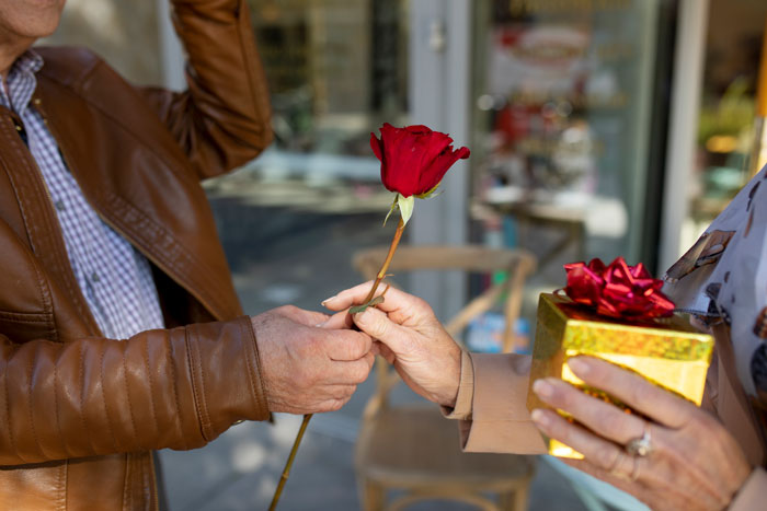 A person hands a red rose to another holding a gift, illustrating common tourist traps with overpriced items. A person hands a red rose to another holding a gift, illustrating common tourist traps with overpriced items.