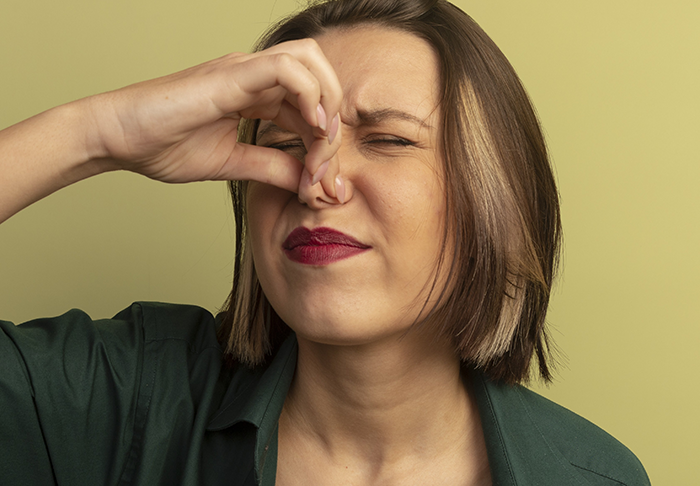 Woman pinching her nose with a disgusted expression, reacting to a mil-try-poison smell or taste. Woman pinching her nose with a disgusted expression, reacting to a mil-try-poison smell or taste.