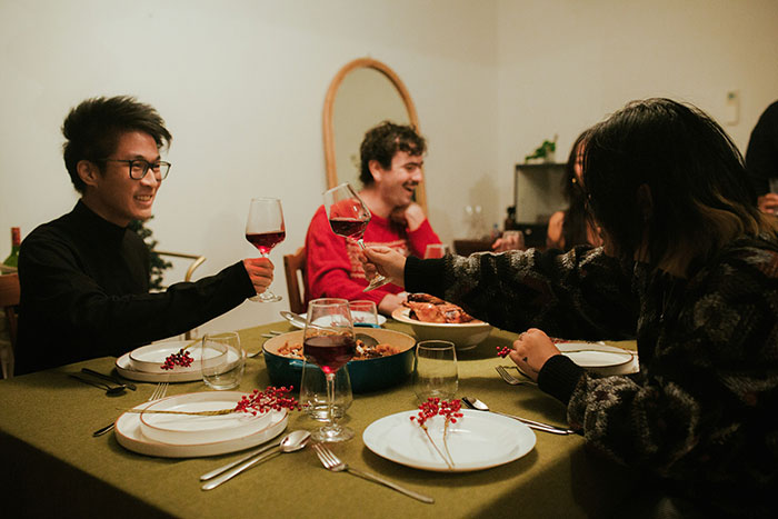 Group of friends enjoying a dinner toast, illustrating family dynamics and challenges with lazy parenting and difficult kids.