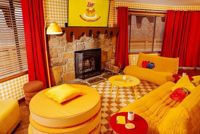 Vintage closet-inspired living room with bright yellow and orange retro furniture, checkered walls, and a stone fireplace.