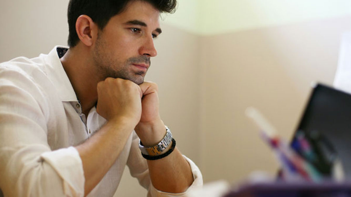 Man in white shirt focused on laptop screen, representing paid companion answering questions about wealthy married women.