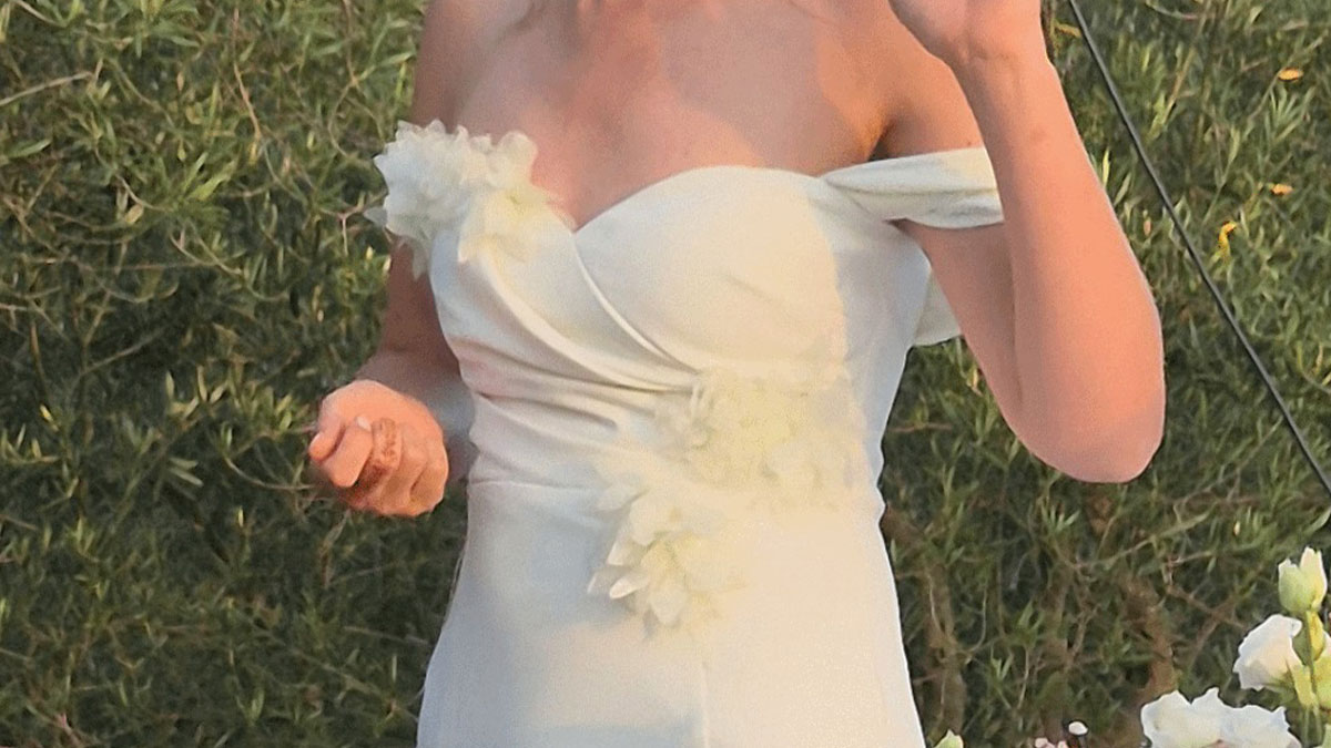 Woman in a white wedding dress with floral details at outdoor wedding, mistaken for wearing sage green dress.