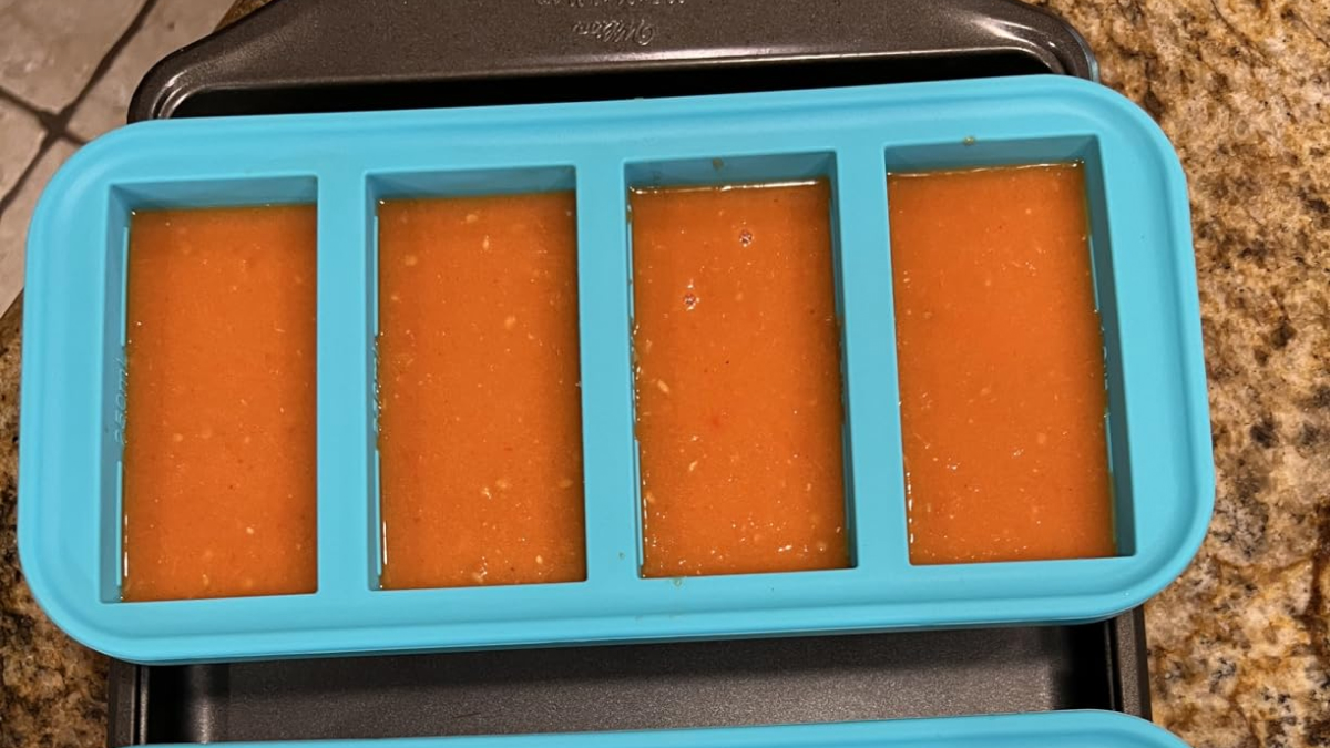 Silicone ice cube tray filled with sauce, demonstrating a weird kitchen invention for easy portion freezing.
