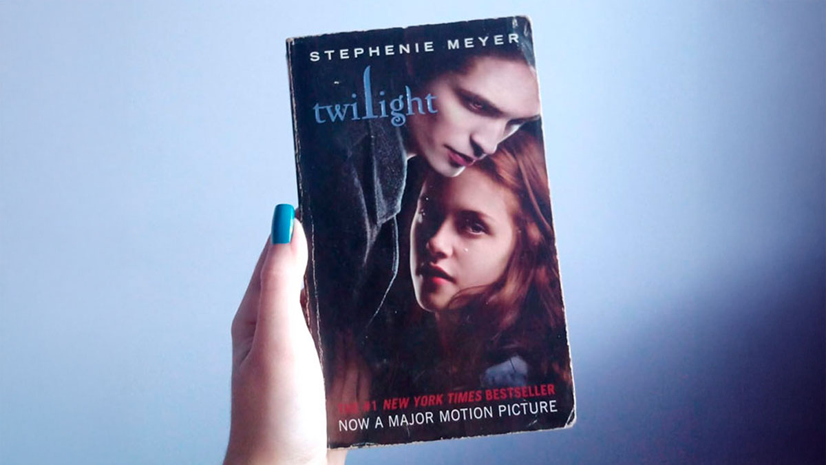 Hand holding a Twilight book against a plain background, illustrating snooping parents uncovering kids' secrets.