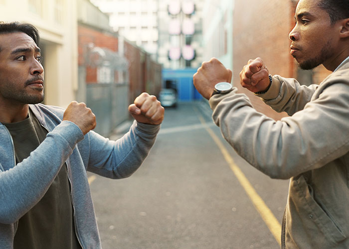 Two men in casual clothes facing off with fists raised, capturing the madness some people witness at work.
