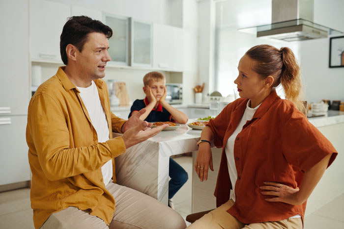 Man and wife having a serious discussion in kitchen about SAHM for teens and household chores with child nearby. Man and wife having a serious discussion in kitchen about SAHM for teens and household chores with child nearby.