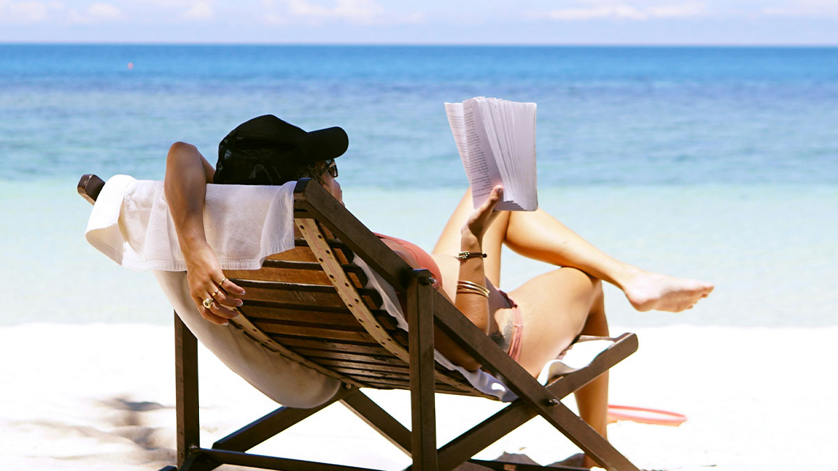 Woman relaxing on a beach chair by the sea, representing an employee off work and missing a meeting.