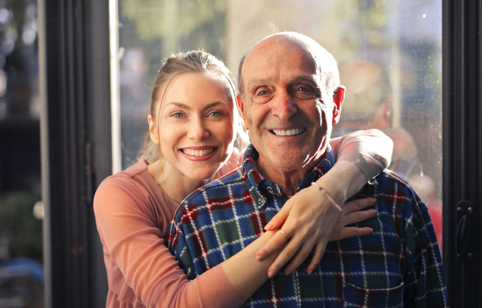 Young woman smiling and hugging her elderly grandpa, highlighting caregiving and family responsibility themes. Young woman smiling and hugging her elderly grandpa, highlighting caregiving and family responsibility themes.