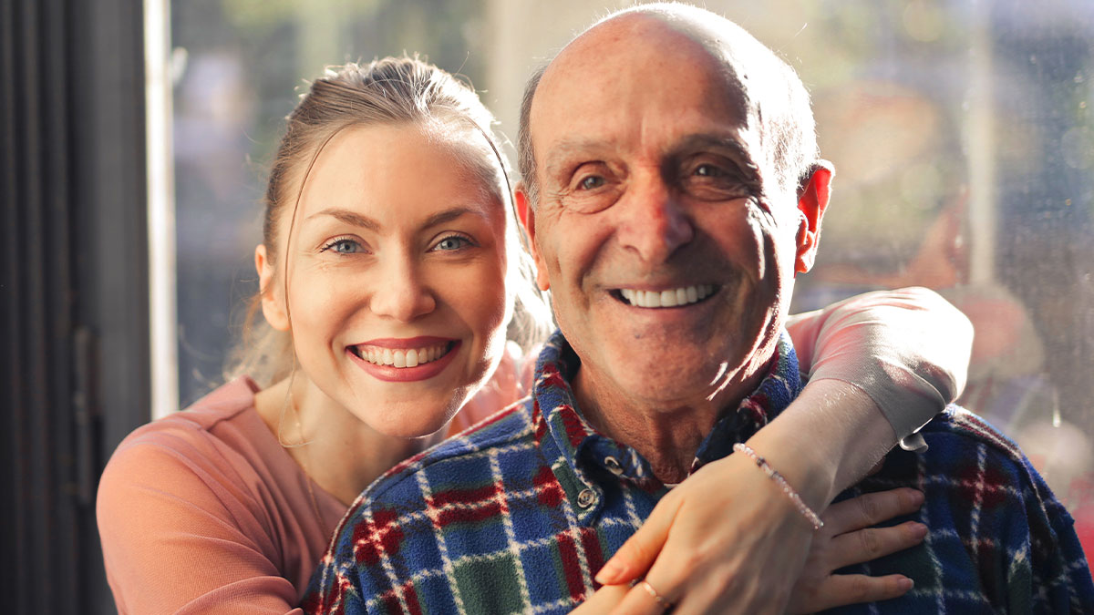 Young woman smiling and hugging elderly grandpa, highlighting years spent caring for him and family tensions.
