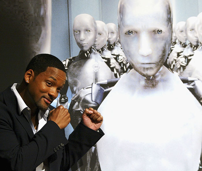 Will Smith posing with robot characters, highlighting a co-actor accusing studio of removing his name from publicity. Will Smith posing with robot characters, highlighting a co-actor accusing studio of removing his name from publicity.